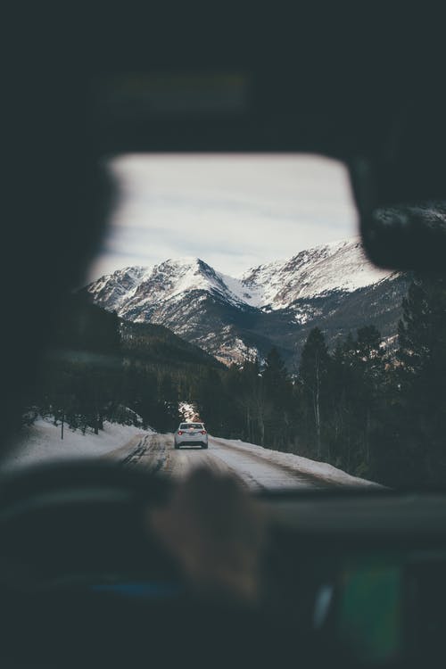 view from car straight ice road with snowy mountains