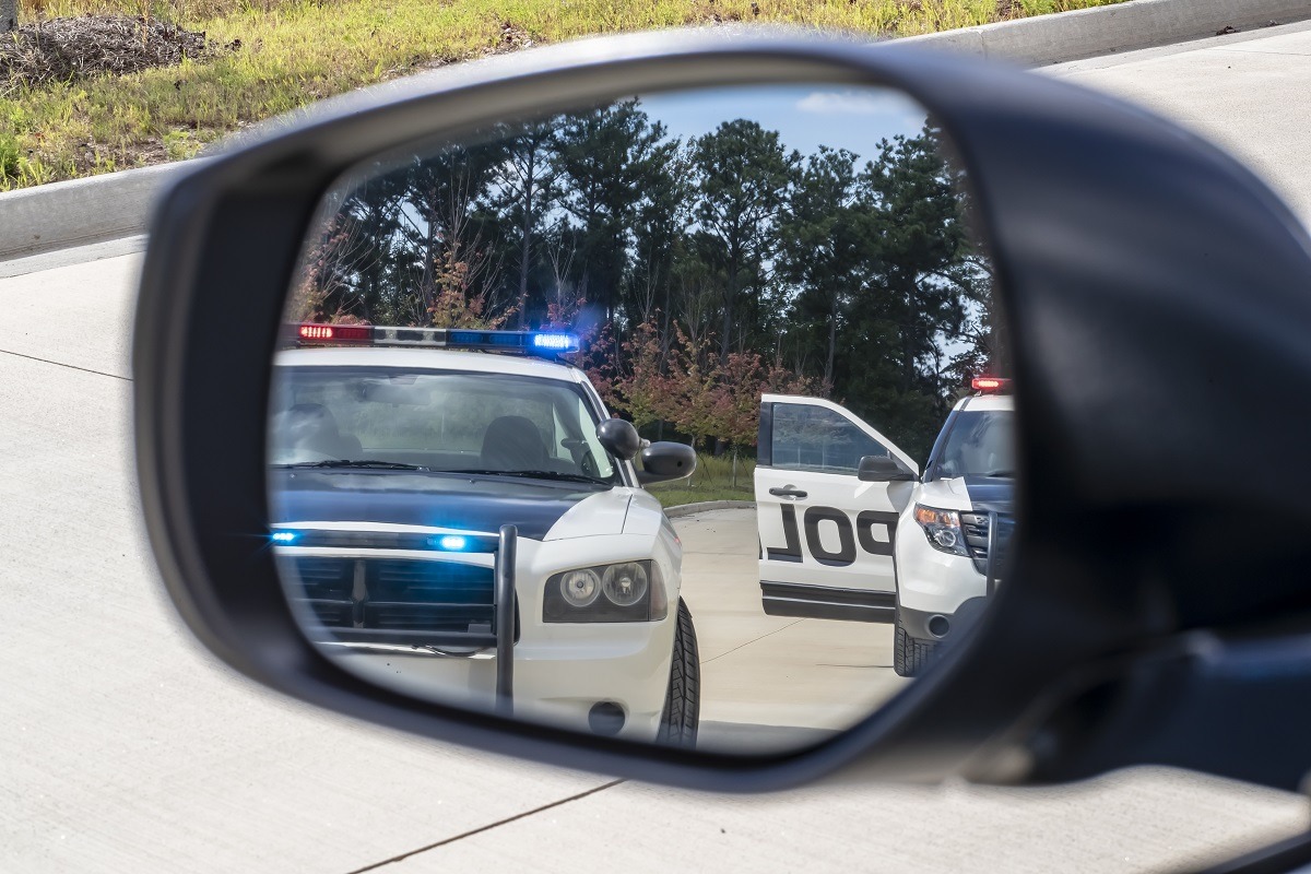 Two police vehicles stop a sedan on a routine traffic stop