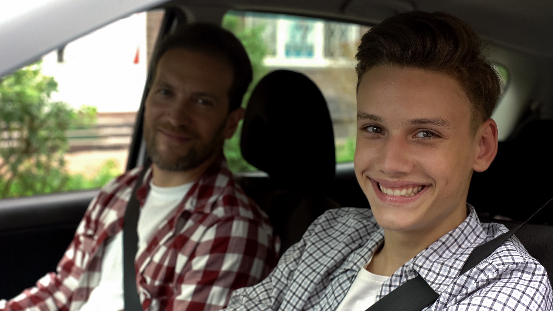 young driver and his father smiling into camera young driver and his father smiling into camera