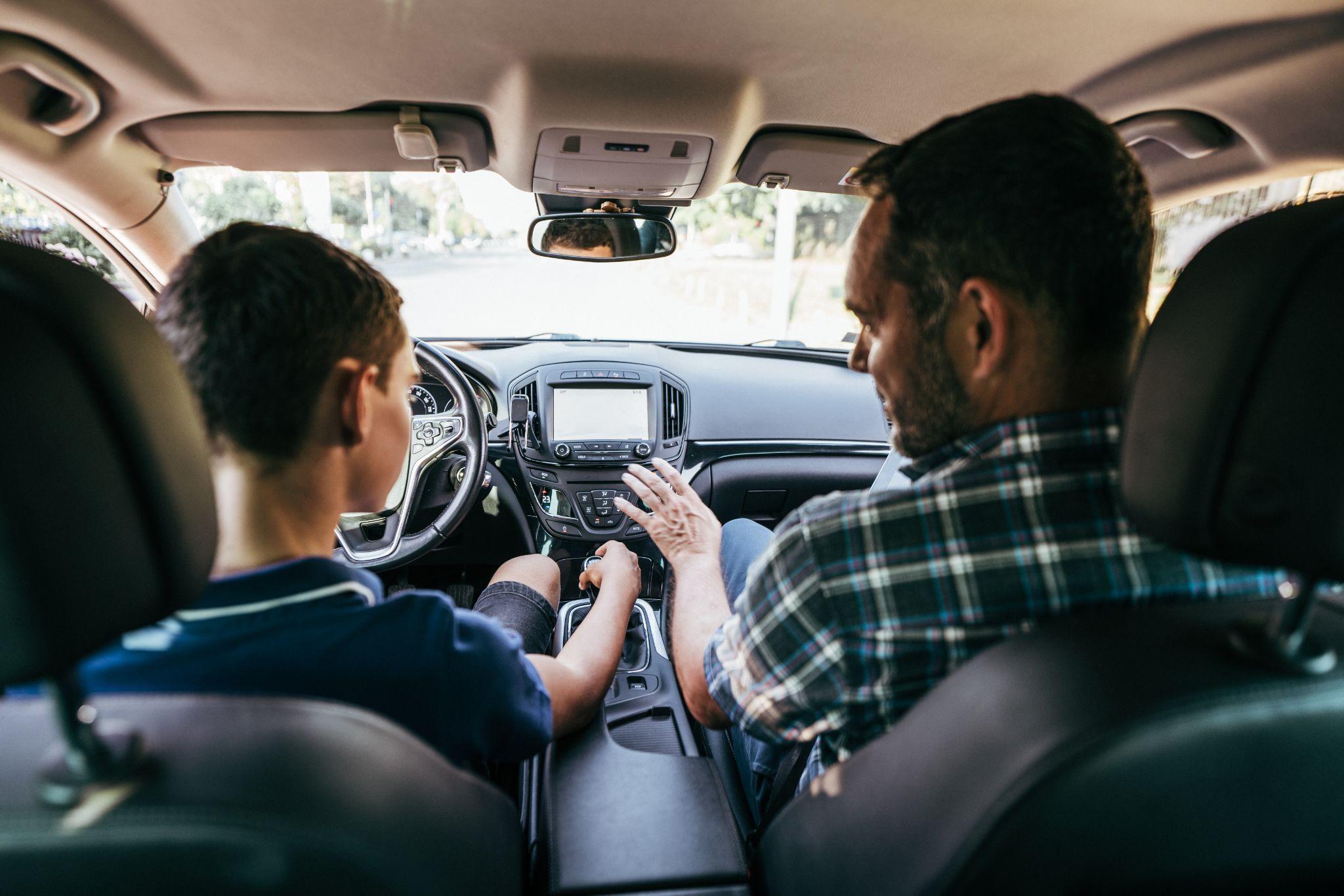 Driving instructor sitting his student and explain to him car driving basics