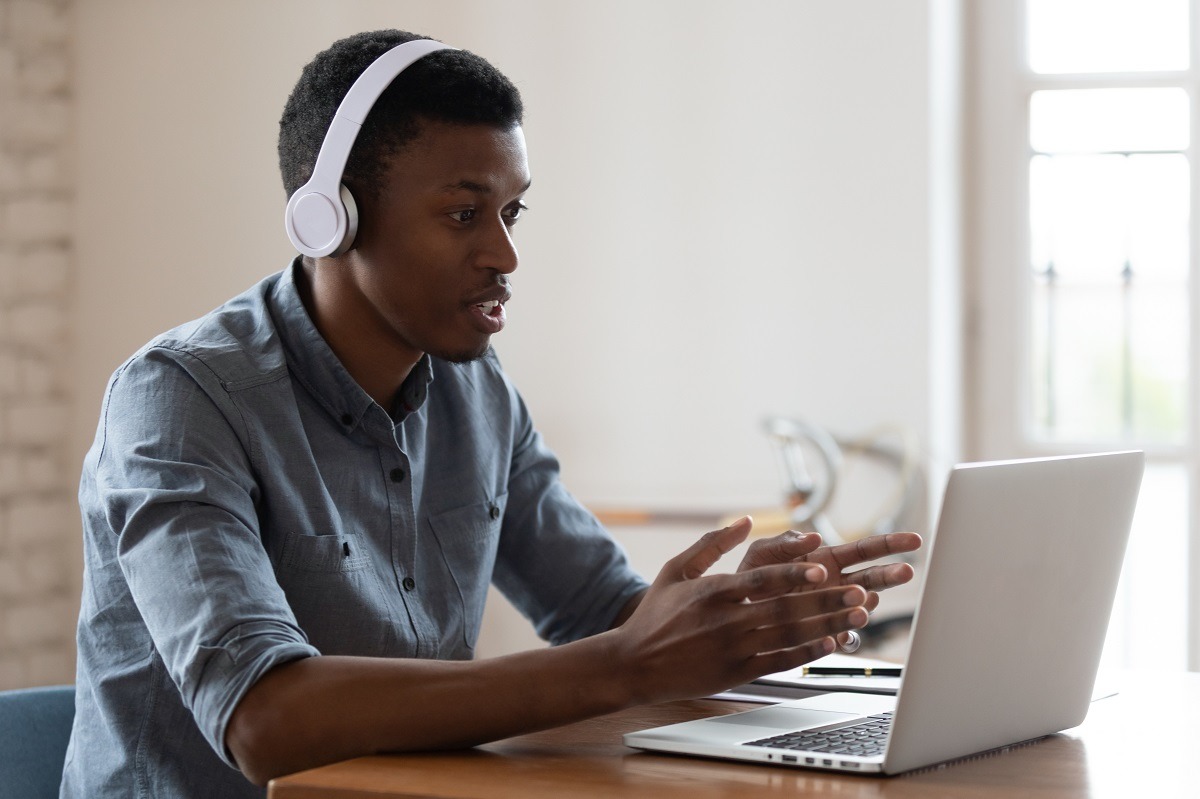 African businessman wearing wireless headphones talking by conference video call