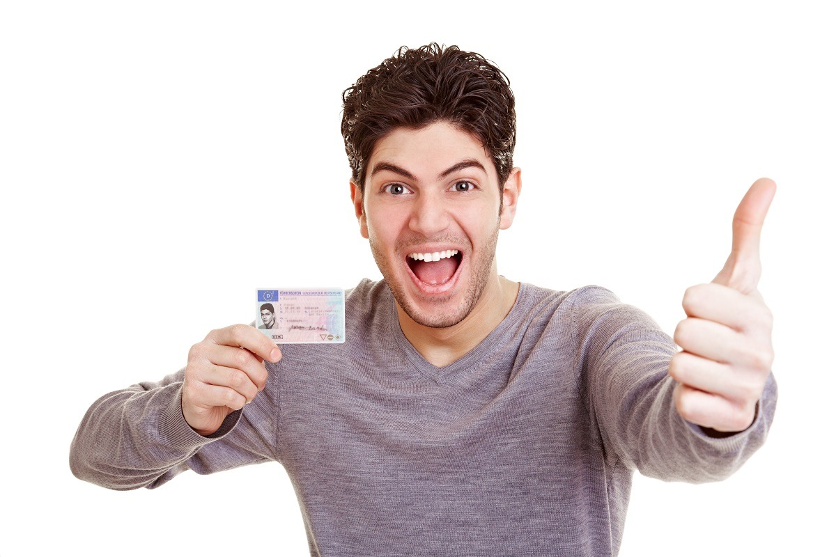 Cheering man with driving license holds his thumb up