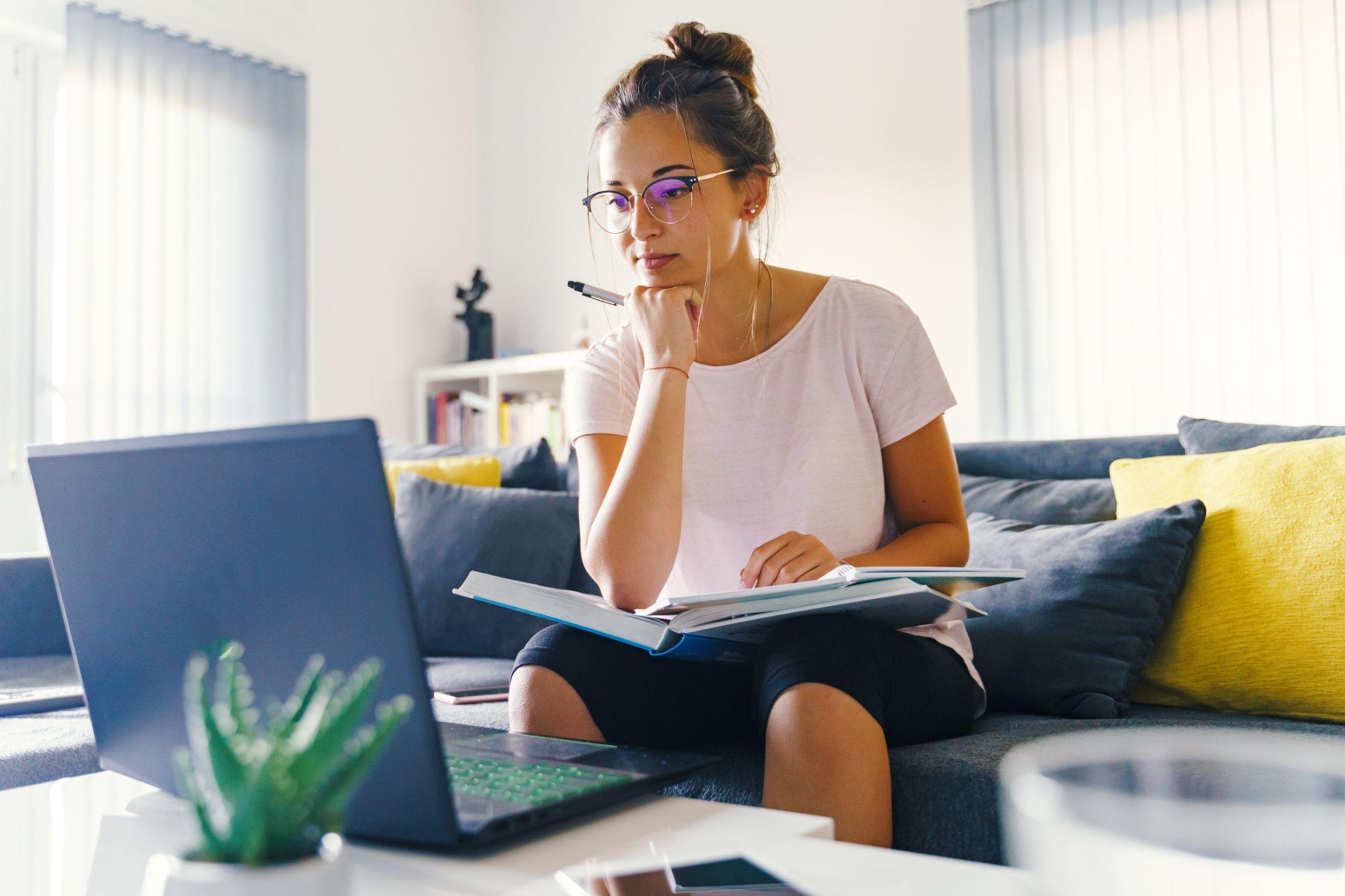 Girl reading book preparing exam test having online consultation