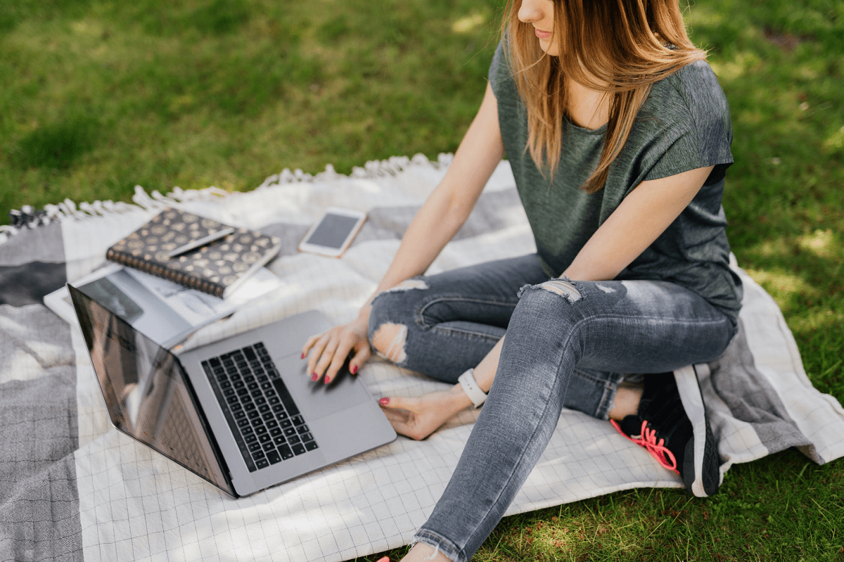 A girl working on laptop and sitting on the glass field park