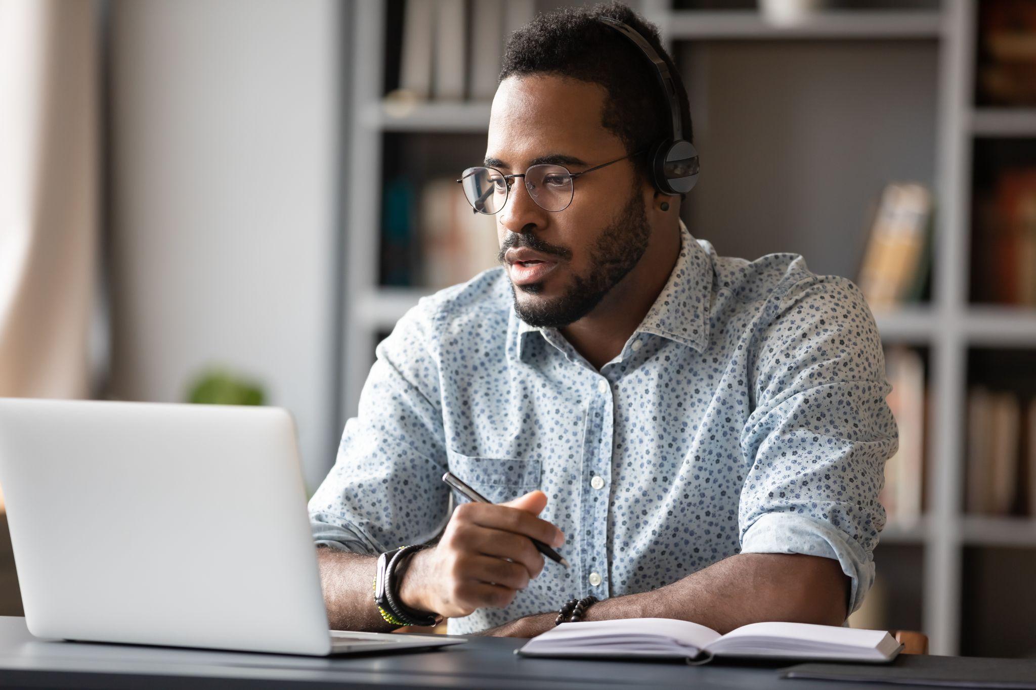 Focused african businessman wear headphones study online