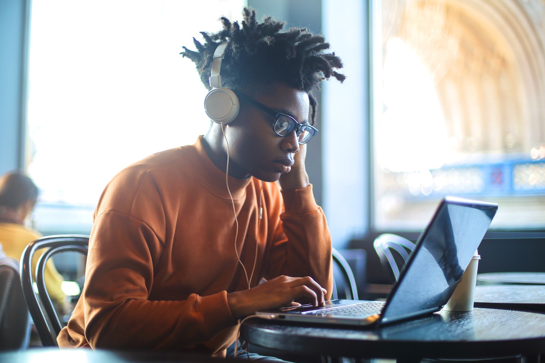 Guy sitting in a bar, listening music and using his laptop