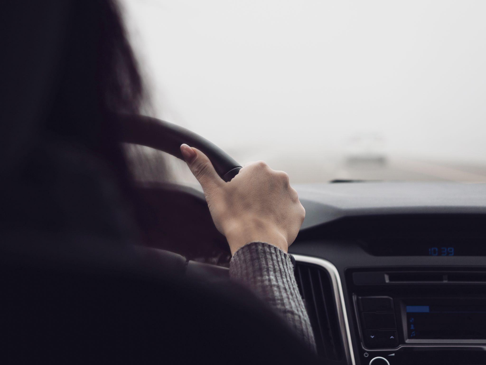 The woman behind the wheel of a car. Poor visibility when driving due to fog.