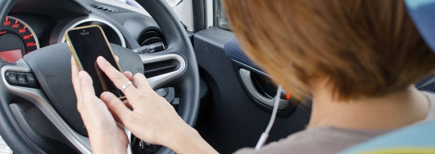 woman using smart phone while driving in car