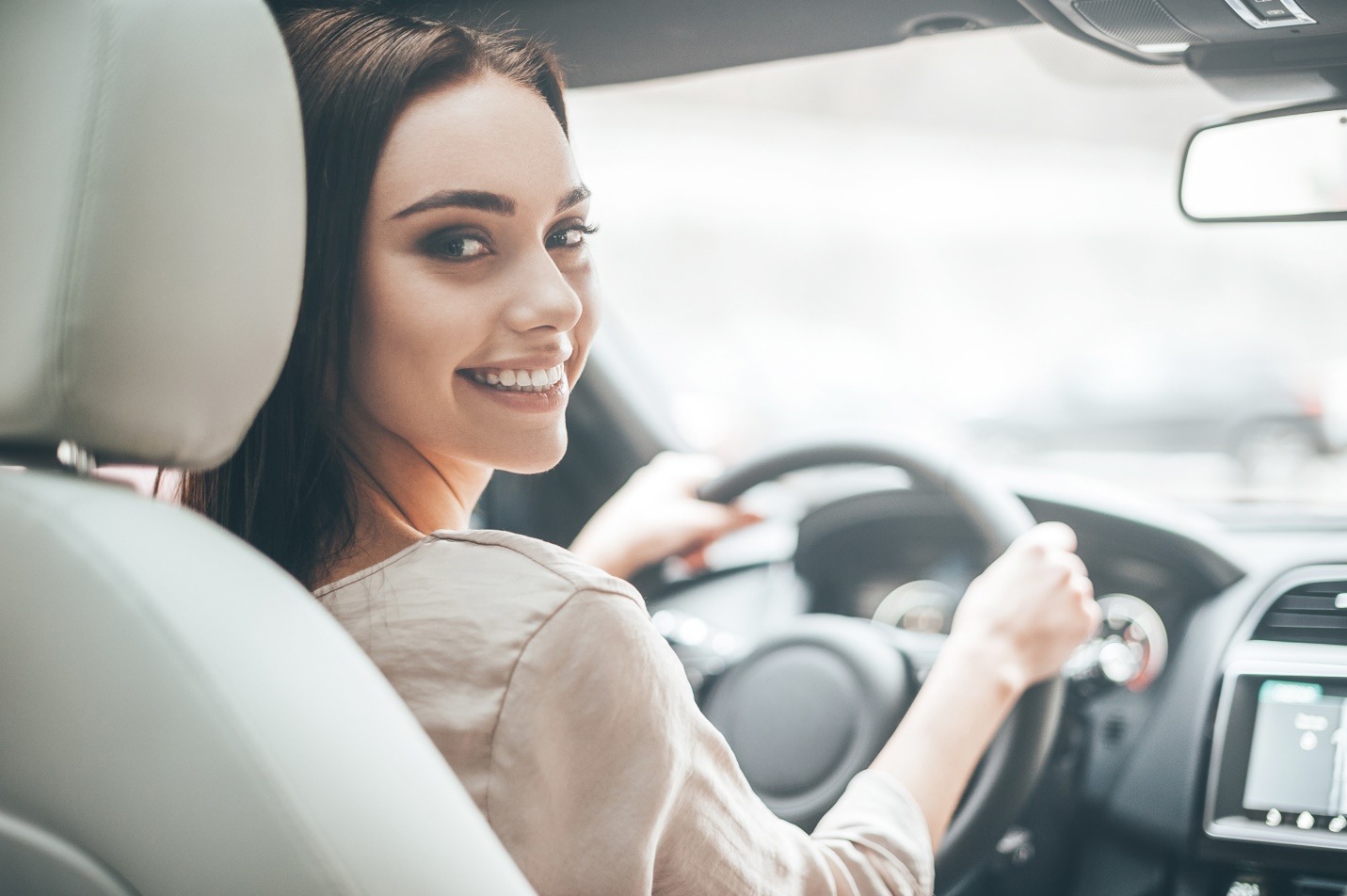 rear view of attractive young woman in car looking over her