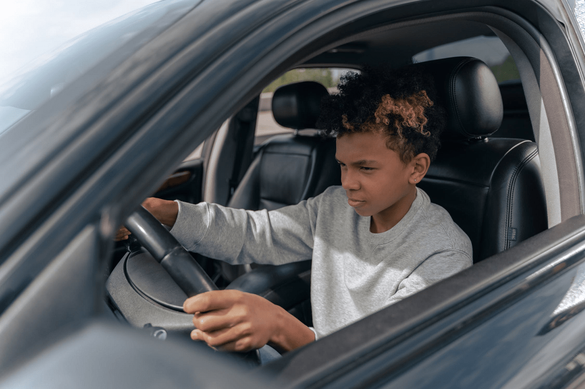 Boy in gray crew neck long sleeve shirt driving car