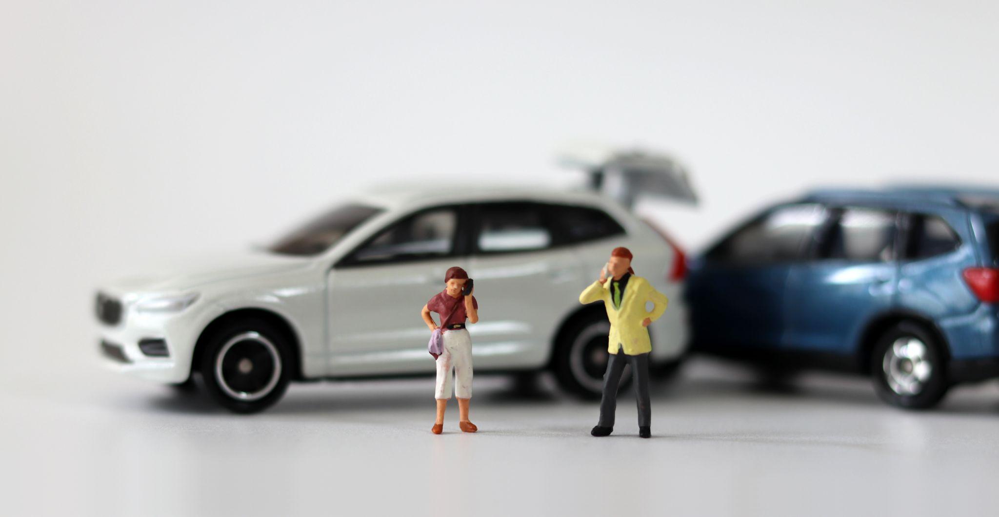 Two miniature cars collided and two miniature people calling. Concepts about car accidents.