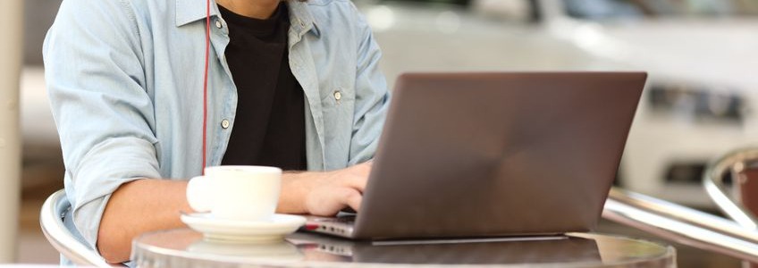 person using a laptop on a small table with coffee