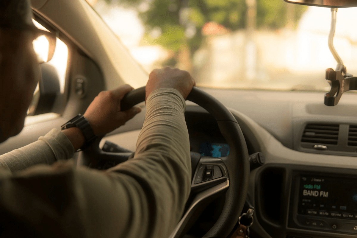 hands of car driver on steering wheel, road trip