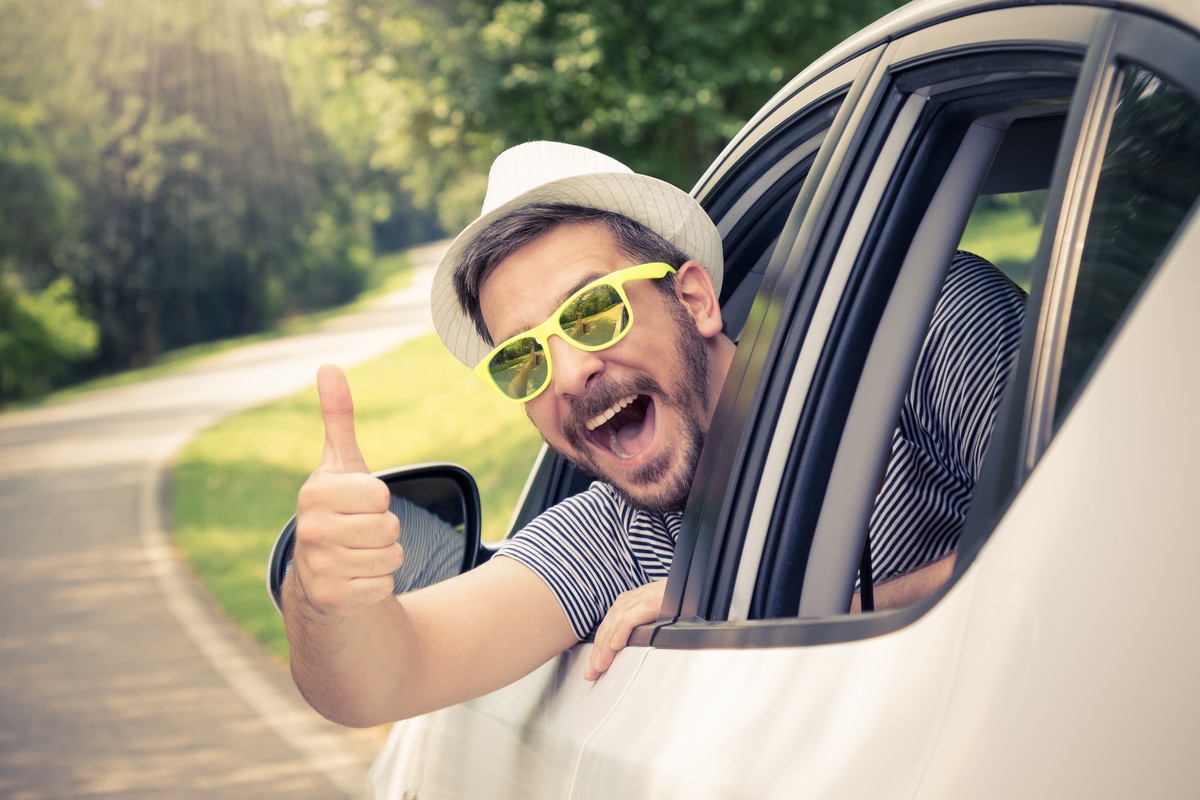 man with sunglasses giving thumbs up from car