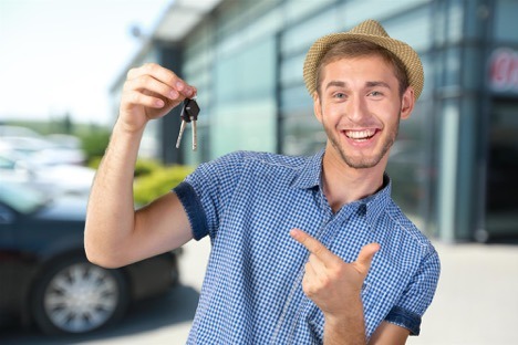 guy holding keys in front of car dealership