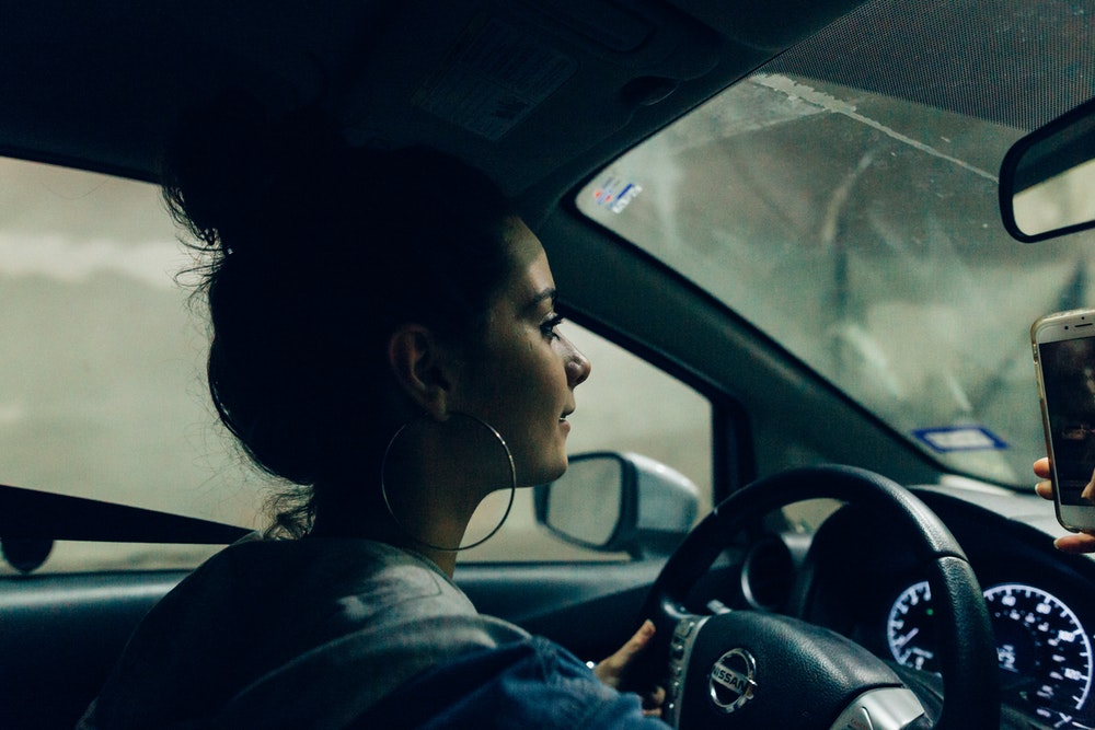 girl reading a text message on mobile while driving