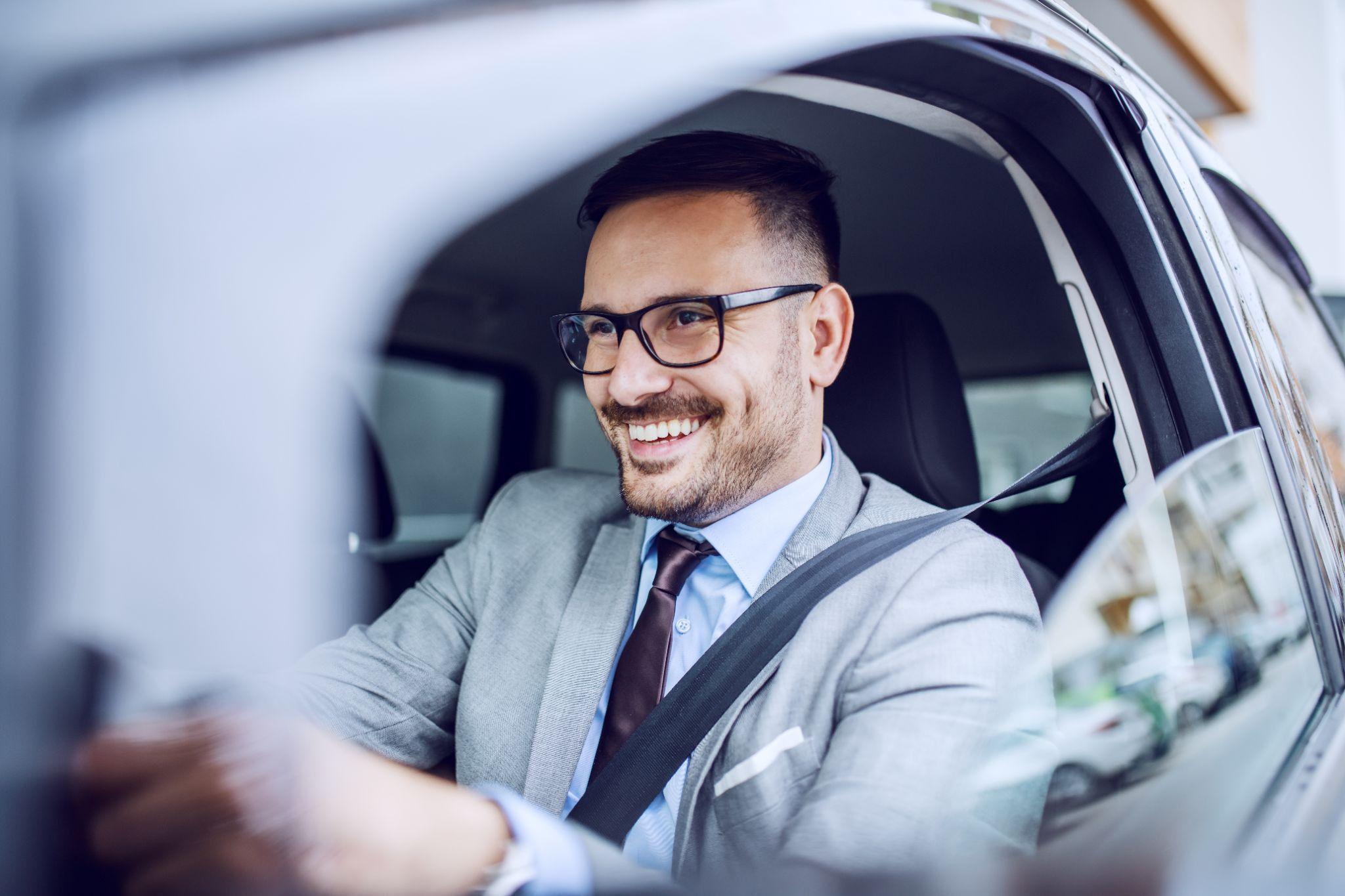 Attractive smiling businessman driving his car.