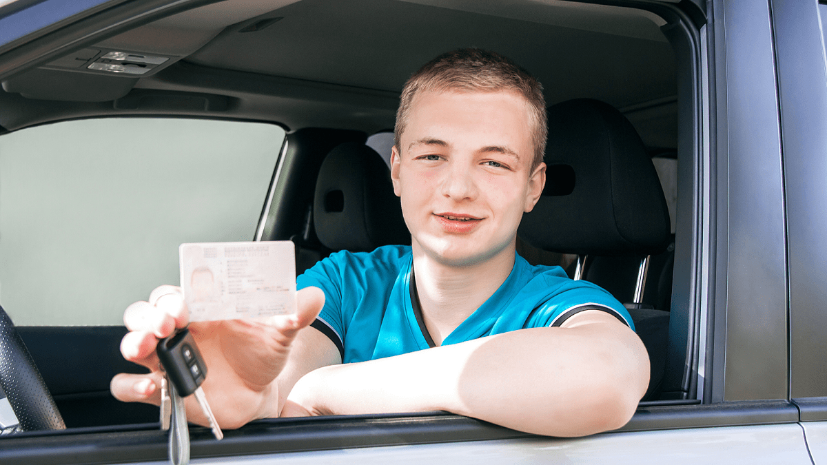 Car driver. Caucasian teen boy showing driver license, car key and car.