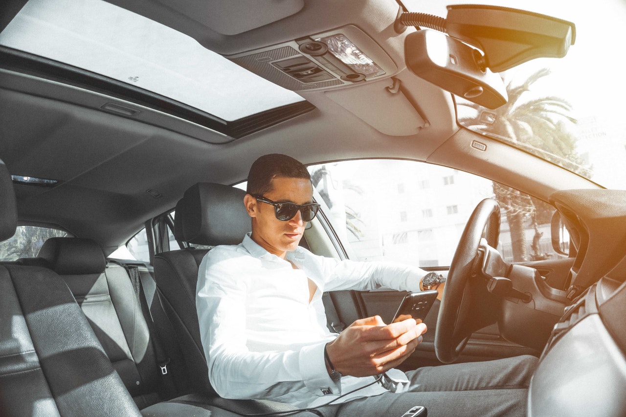 young man driving his car while texting