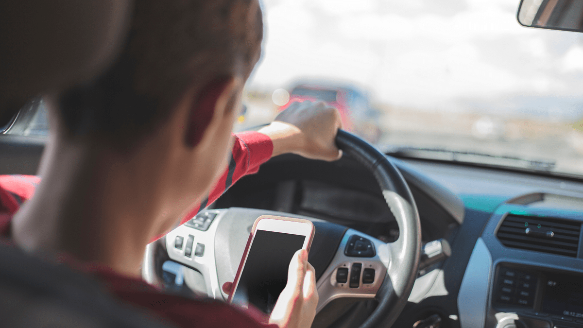 young man holding a phone while driving