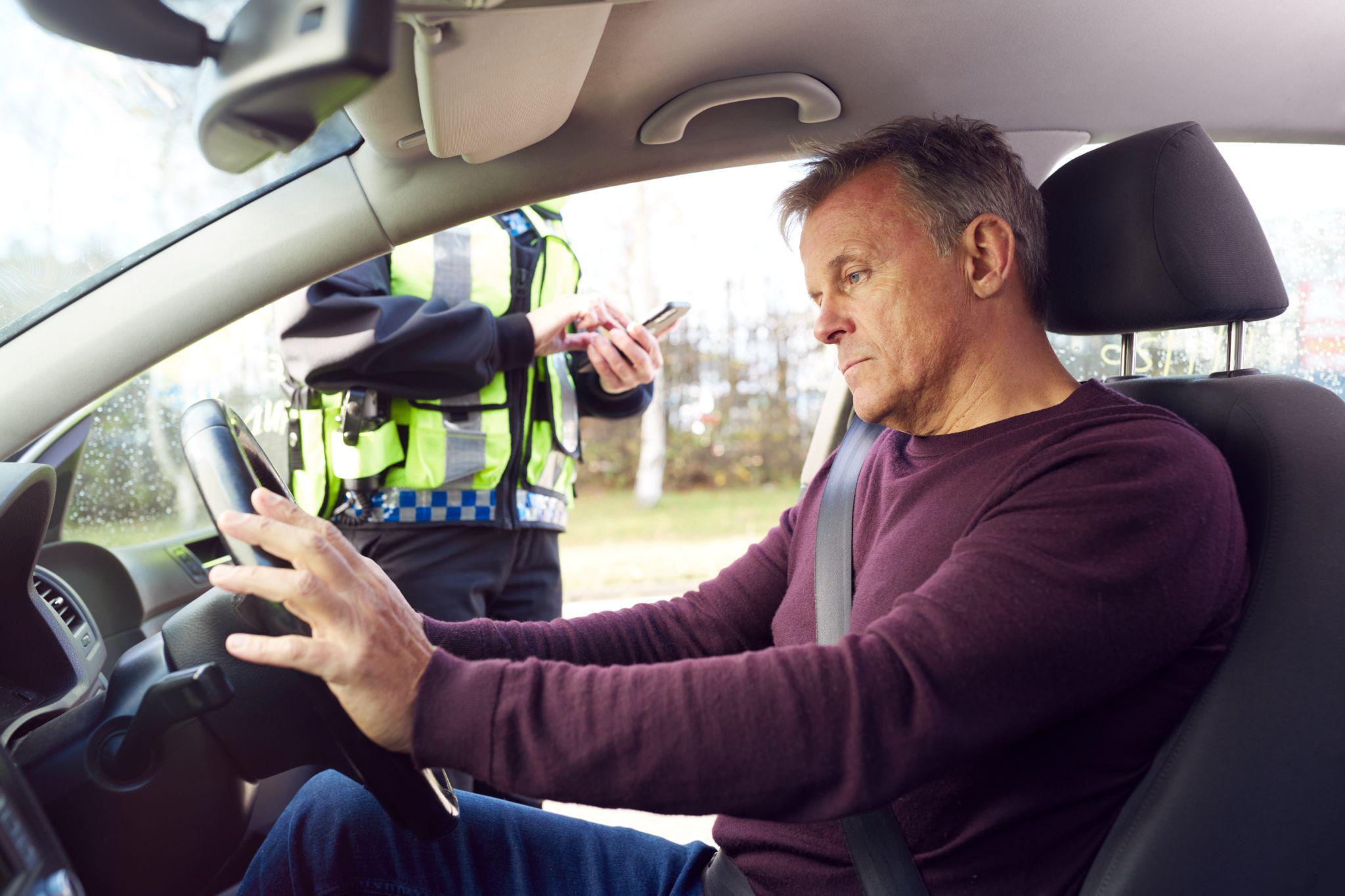 Driver being stopped by traffic police officer with digital tablet for driving offence