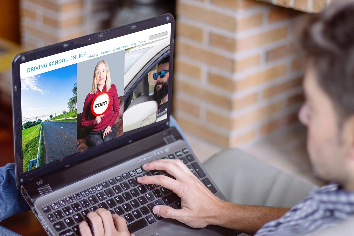 Man at home using laptop with driving school website on the screen