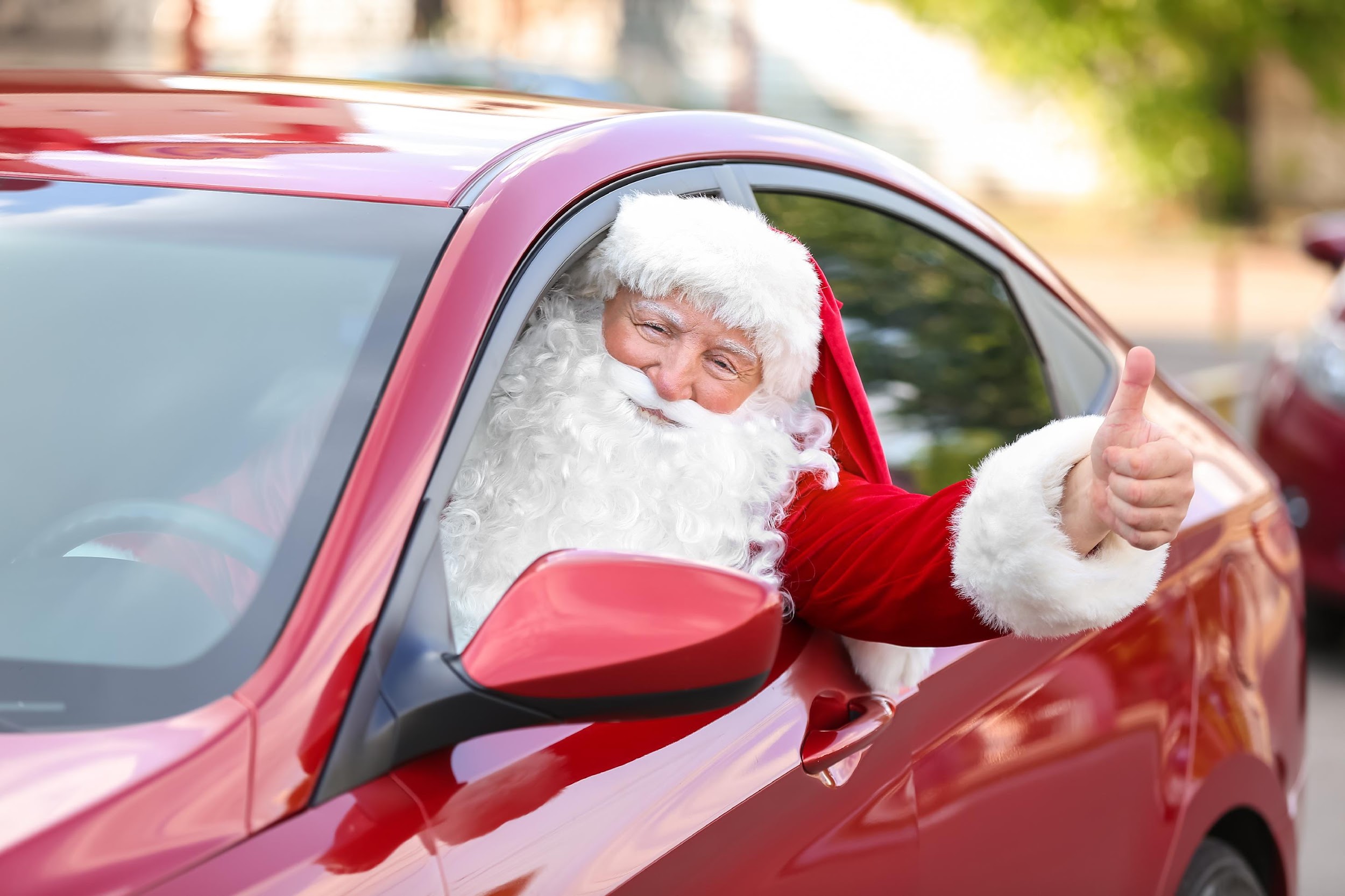 Santa Claus showing thumb-up while driving car