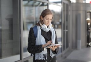 Woman in Black Fur Coat While Holding Tablet