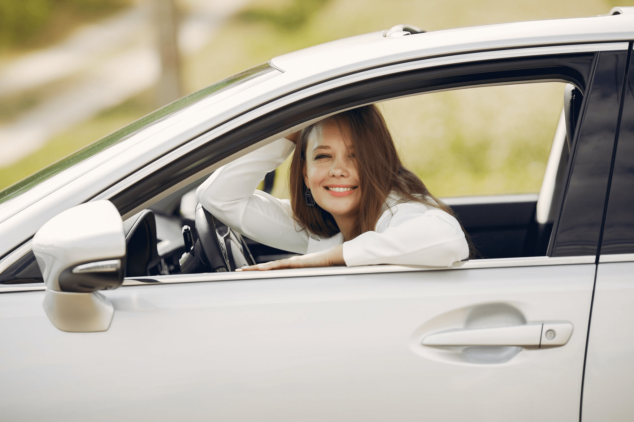Happy young woman sitting in the car smiling at the camera