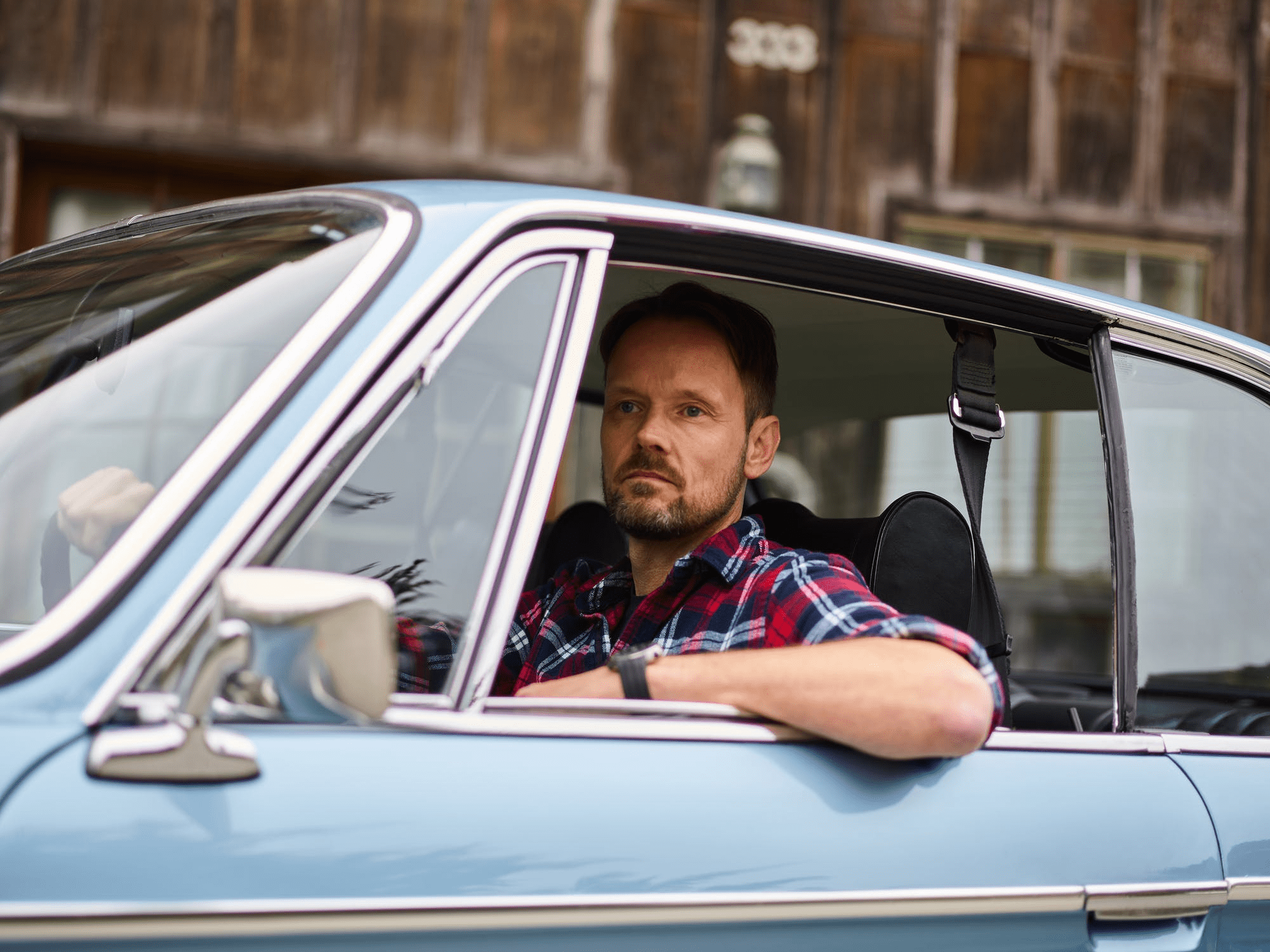 Satisfied bearded man driving a car