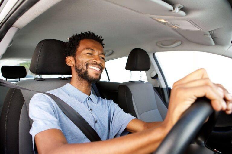 Man driving car and smiling. 