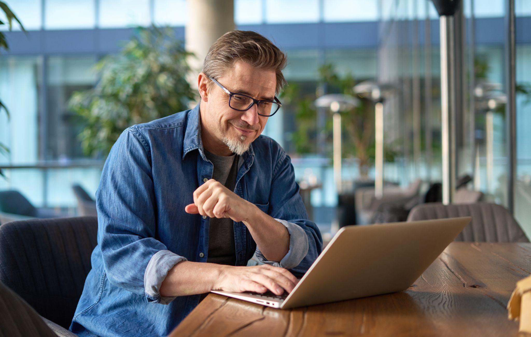 Happy middle age businessman using laptop computer in office