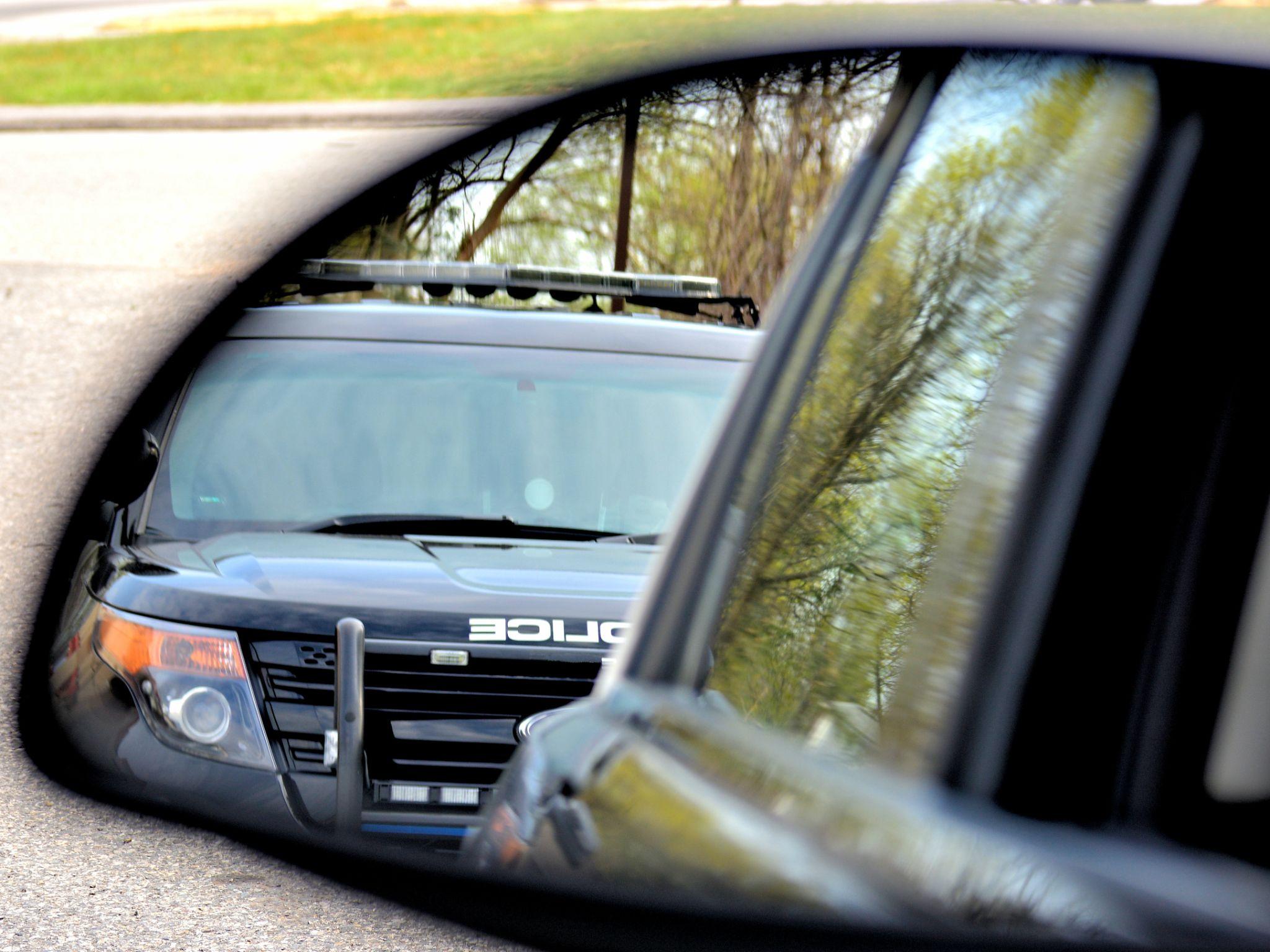 A police car has a motorist stopped for a violation. the drivers view from his side mirror